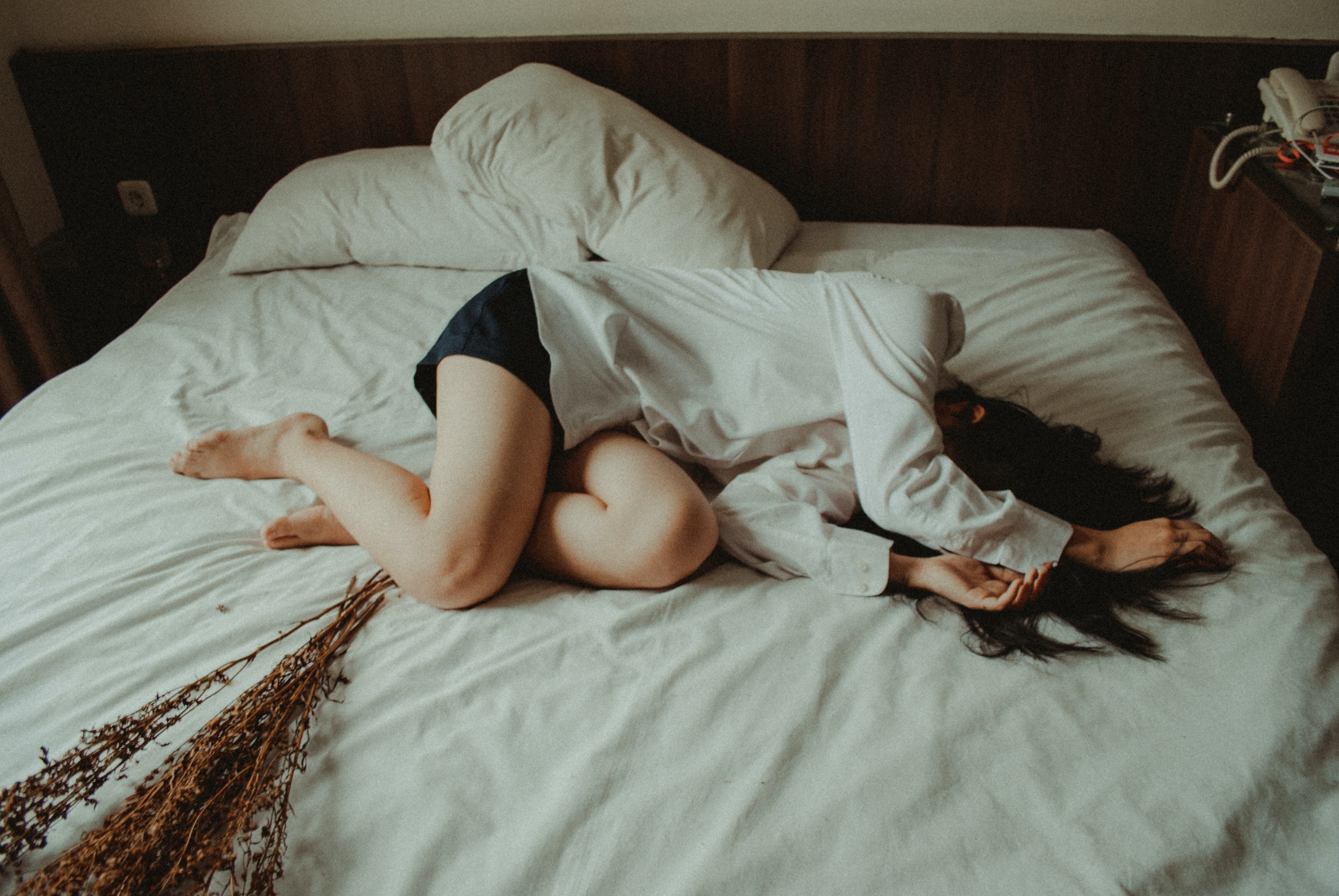 burnout-metaphor-woman-curled-up-in-bed-covering-her-face